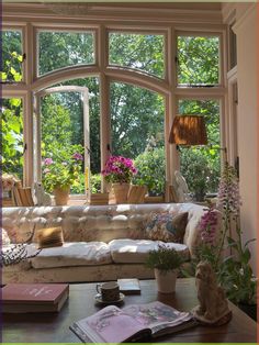 a living room filled with lots of furniture and flowers in front of a large window