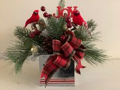 a christmas centerpiece with pine cones, berries and cardinal decorations in a metal container