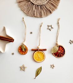 three ornaments made out of dried orange slices and cinnamon sticks on a white surface with star decorations