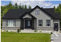 a gray house sitting in the middle of a lush green field