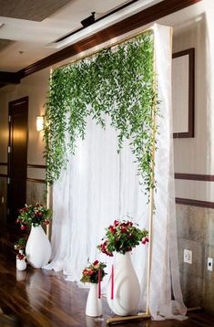 an arrangement of flowers and greenery on display in front of a white drape