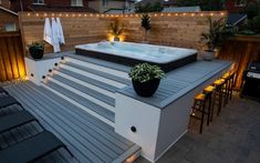 a hot tub sitting on top of a wooden deck next to a bar and chairs