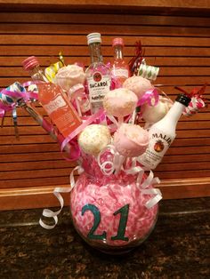 a pink vase filled with lots of different types of liquor and sweets on top of a table