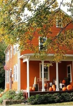 an orange house with pumpkins on the porch