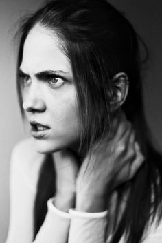 a black and white photo of a woman with her hand on her shoulder looking at the camera