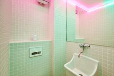 a bathroom with green and pink tiles on the walls, white fixtures and a sink