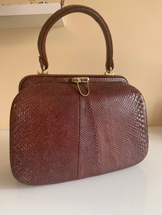 "A very well made quality and stylish handbag. In an exotic leather. Timeless styling for any vintage handbag collector and lover. Also a great piece to start your vintage handbag love story. Quality hardware that has stood the test of time although of course some wear it noted but I think it really just adds charm and character to this bag. The handbag has a slightly rough texture as you would expect from this kind of leather. Condition is very good vintage, of course some wear is noted. W 10.5\" H 8\" D 4\"" Retro Rectangular Bag With Leather Lining, Retro Top Handle Bag In Vintage Brown, Vintage Brown Handheld Shoulder Bag, Retro Vintage Brown Top Handle Bag, Retro Top Handle Bag With Leather Lining, Retro Top Handle Shoulder Bag With Leather Lining, Retro Shoulder Bag With Top Handle And Leather Lining, Vintage Textured Leather Bags, Classic Rectangular Shoulder Bag In Vintage Style