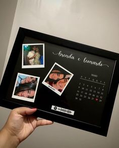 a person holding up a black framed calendar with photos on the front and back of it