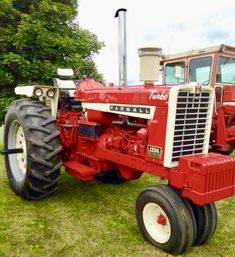 a red tractor parked on top of a lush green field