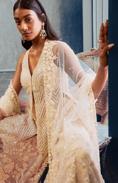 This sharara set features three-dimensional floral sequin, pearl and crystal embroidery. The outfit is paired with embellished v neck top and a four-sided embroidered net dupatta.From Seema Gujral’s Fiori collectionDELIVERY TIMEPlease allow 8-12 weeks for your outfit to arriveFABRIC DETAILSNetProfessional cleaning only Anarkali Palazzo Set With V-neck For Wedding, Wedding Anarkali Palazzo Set With V-neck, V-neck Resham Embroidery Palazzo Set For Wedding, V-neck Sheer Dupatta For Diwali, V-neck Dress With Mirror Work For Reception, Anarkali Set With Sheer Dupatta And V-neck, Eid Sets With Sheer Dupatta, Glamorous Floor-length Sharara With Resham Embroidery, Glamorous Dress With Dupatta For Eid