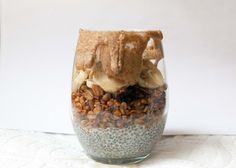 a glass filled with food sitting on top of a white table next to a wall