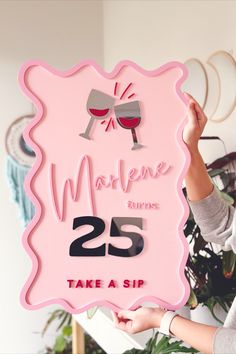 a woman holding up a sign that says marquee express 25 take a sip