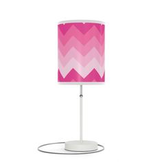 a pink and white chevron lamp on a white base with a light plugged in