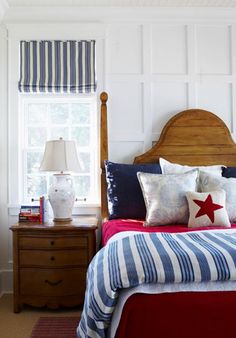 a bed in a bedroom with blue and white striped bedspread, red pillow cases, and two nightstands