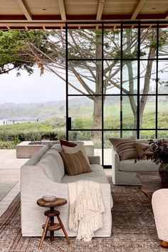 a living room filled with furniture next to a large glass wall window covered in lots of windows