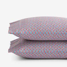 two pillows on top of each other in front of a white background with blue and red designs