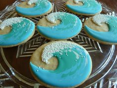 cookies decorated with blue icing and white sprinkles on a glass plate