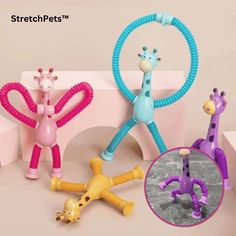 three toy giraffes are shown in different colors and sizes, including one with a hoop