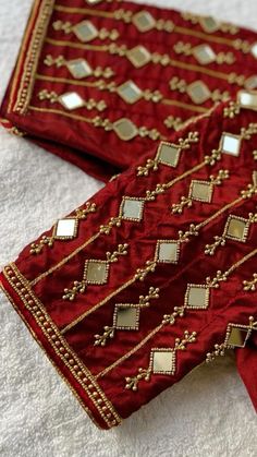 two pieces of red and gold cloth on a white surface