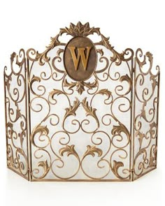 an ornate gold and white fireplace screen with the letter w on it's side