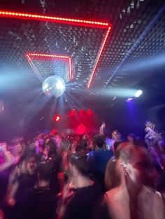 a group of people are dancing at a party with disco lights and mirrors on the ceiling