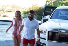 a man and woman walking next to a white truck