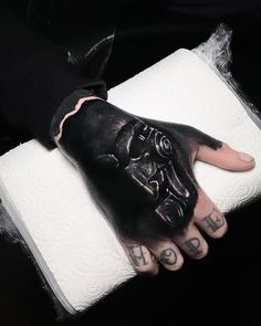 a person's hand is covered in black ink and has a mask on it