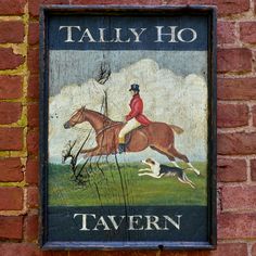 a sign on the side of a brick building with a horse and dog running in front of it