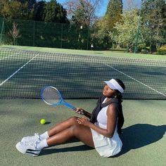 a woman is sitting on the tennis court with her racket and ball in hand