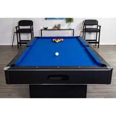 a blue pool table in a room with chairs and a painting on the wall behind it