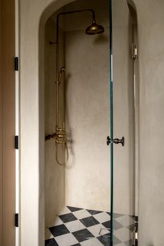 a bathroom with a checkerboard floor and glass shower stall in the corner between two walls