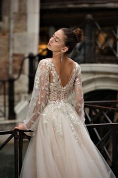 a woman in a wedding dress leaning on a railing