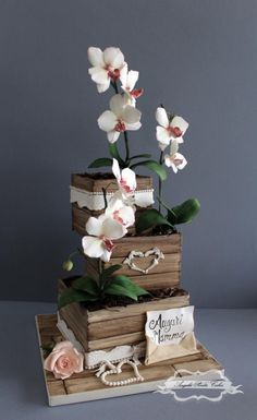 a three tiered wooden box with flowers on the top and two cards attached to it