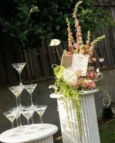 there is a vase with flowers and wine glasses on the table next to each other