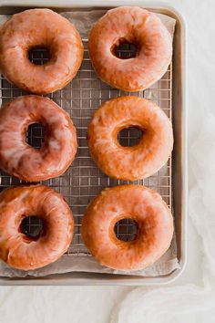 six glazed doughnuts on a cooling rack ready to be baked in the oven