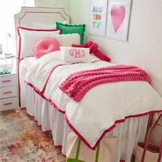 a white bed with pink and green pillows