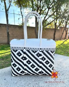 a black and white handbag sitting on top of a cement slab next to trees