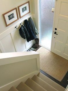 there is a coat rack on the wall next to the stairs in this entryway