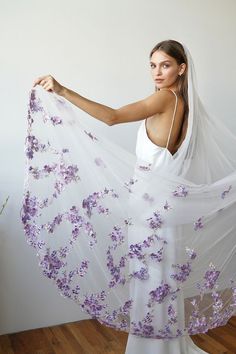 a woman in a white dress holding a purple flowered shawl over her shoulder