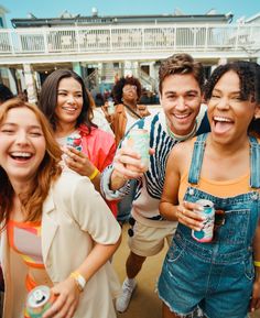 a group of people standing next to each other holding cans and smiling at the camera