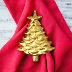 a gold christmas tree brooch sitting on top of a red napkin