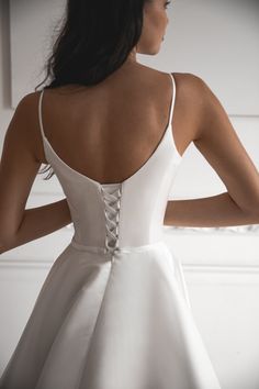 the back of a woman's white wedding dress, with her hands on her hips