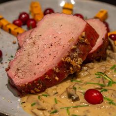 a white plate topped with meat covered in gravy and garnished with cranberries