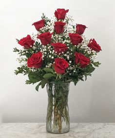 a vase filled with red roses and white baby's breath