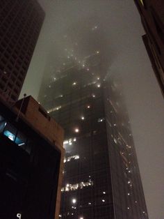 skyscrapers are lit up in the fog at night