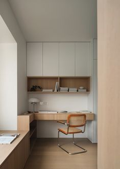 a chair sitting in front of a desk with a book shelf above it and cabinets behind it