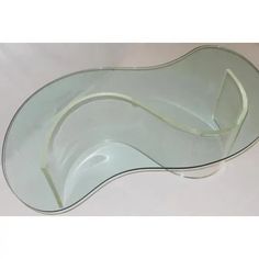 an oval glass dish with curved edges on a white tableclothed surface, in the shape of a wave