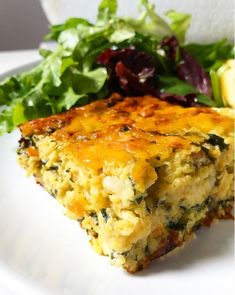 a white plate topped with a slice of quiche next to a leafy green salad