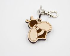 a wooden keychain with a bee design on the front and back of it