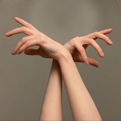 two hands reaching out towards each other in front of a gray background with the same person's arms